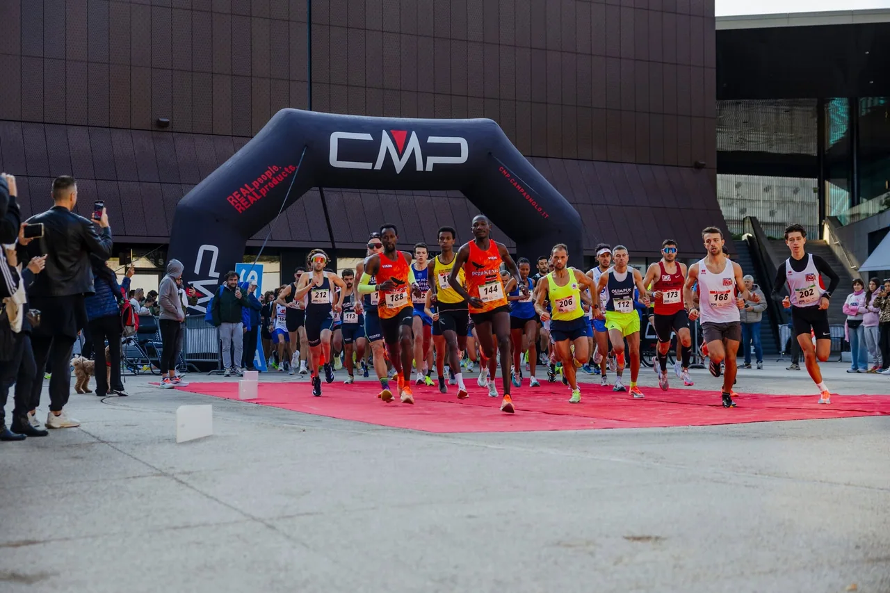 Il gruppo di atleti parte sotto l’arco della SMOE Run 2025